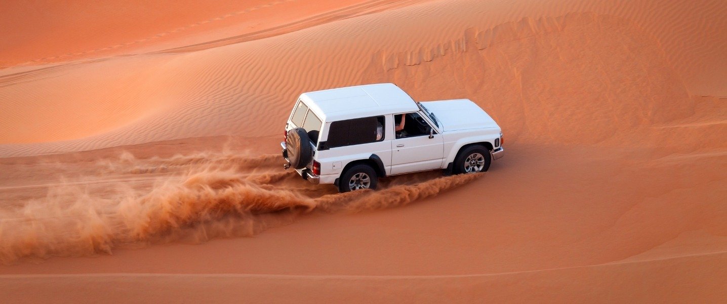 Tourists enjoying dune bashing in 4x4 SUV during Dubai Desert Safari