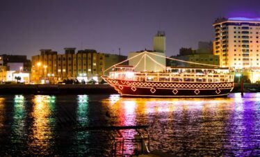 Traditional wooden dhow cruising through Dubai Marina with glittering skyscrapers in the background